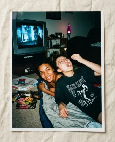 Nostalgic Flash — 2000s Sleepover / Movie Night 1 — Nano Banana AI Prompt: Two friends in a dark living room during a sleepover — a young person with short...