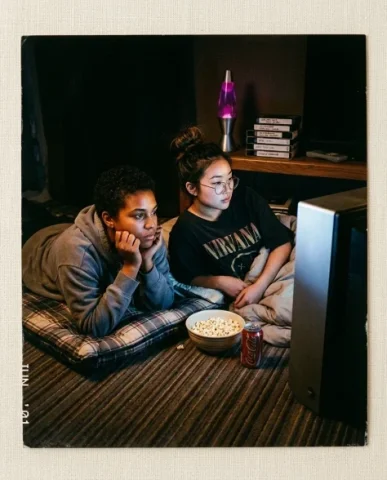 Nostalgic Flash — 2000s Sleepover / Movie Night 2 — Nano Banana AI Prompt: Two friends mid-pillow fight in a living room during a sleepover — a young perso...