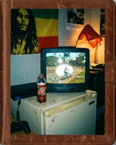Gaming Buddies — PS2 Era, 2004 5 — Nano Banana AI Prompt: Two friends in a playful scuffle on the low futon in a college dorm room — a tal...