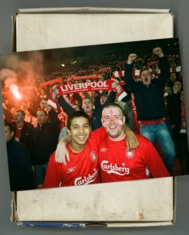 Stadium — Champions League Night, 2005 1 — Nano Banana AI Prompt: Two friends — a young person with short dark hair and warm brown skin, and a sto...