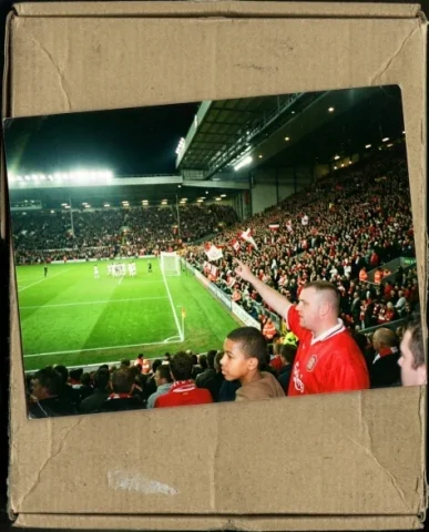Stadium — Champions League Night, 2005 5 — Nano Banana AI Prompt: Two friends — a young person with short dark hair and warm brown skin, and a st...