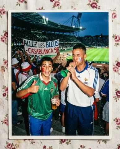 Stadium — World Cup, 1998 1 — Nano Banana AI Prompt: Two friends — a young person with short dark hair and warm brown skin, and a sli...
