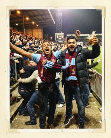 Stadium — Local Derby, Friday Night, 2012 3 — Nano Banana AI Prompt: Two friends at the halftime pie stand — a young person with short dark hair and...