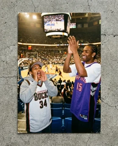 Courtside — NBA Game, 2003 2 — Nano Banana AI Prompt: Two friends in the lower bowl of an NBA arena during halftime — a young person w...