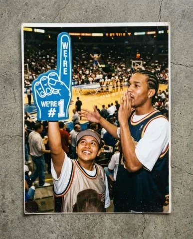 Courtside — NBA Game, 2003 3 — Nano Banana AI Prompt: Flash catches the foam finger and their theatrical poses. Film grain, warm color...
