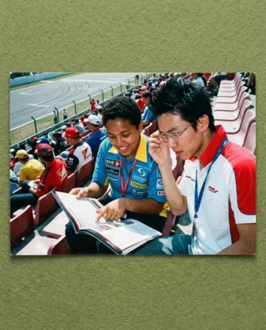 Pit Lane — F1 Race, 2008 3 — Nano Banana AI Prompt: Two friends posing at a team merchandise stand at the F1 circuit — a young perso...