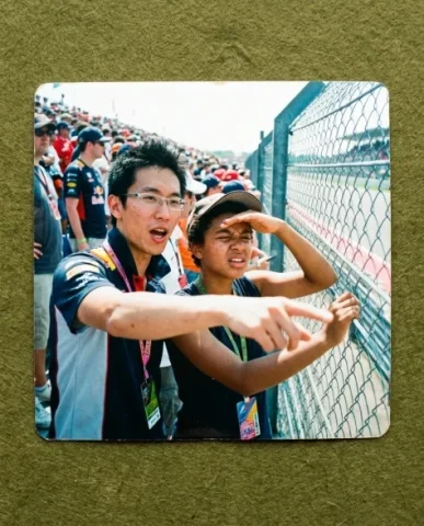 Pit Lane — F1 Race, 2008 6 — Nano Banana AI Prompt: Close-up of two hospitality passes and lanyards held up to the camera — a young...