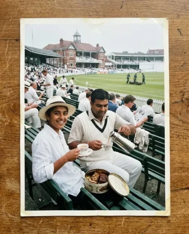 Cricket Ground — Test Match, 2001 3 — Nano Banana AI Prompt: Two friends in the members' stand — a broad-shouldered South Asian man with a ne...