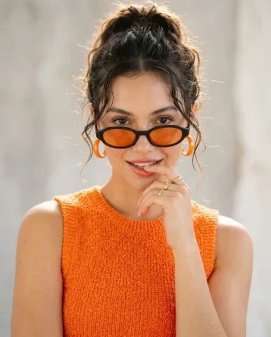 High-Fashion Editorial Portrait with Vivid Tangerine Accents 2 — Nano Banana AI Prompt: Narrow oval sunglasses featuring a matte black frame with vivid tangerine-tinted...