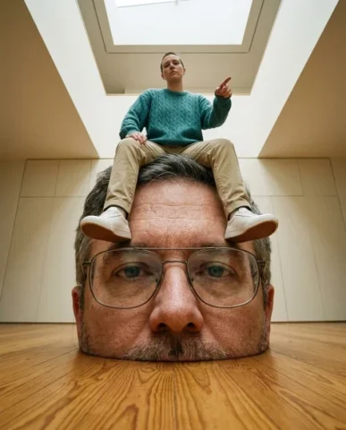 Surreal Conceptual Portrait with Scale Distortion 2 — Nano Banana AI Prompt: From this perspective the giant head looms large in the foreground, its spectacl...