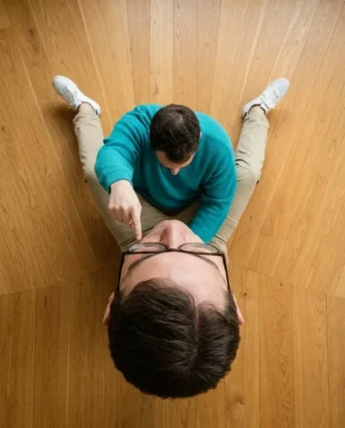Surreal Conceptual Portrait with Scale Distortion 7 — Nano Banana AI Prompt: The giant head rests on the floor with its spectacles slightly askew, skin rende...