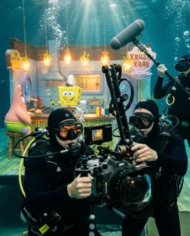 Behind-the-Scenes Underwater Cartoon Film Set 3 — Nano Banana AI Prompt: Their polished diving equipment catches the underwater light — regulators produc...