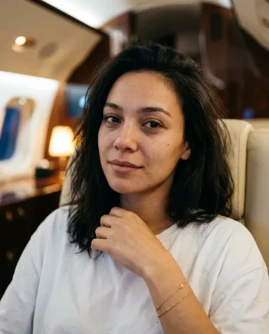 Luxury Private Jet Cabin Lifestyle Portrait 3 — Nano Banana AI Prompt: Cool blue-white exterior light from the window illuminates her near cheek, jawli...