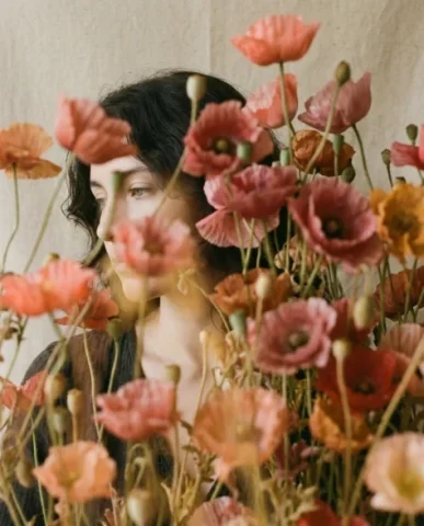 Soft Artistic Portrait with Flowers and Dreamy Blur 6 — Nano Banana AI Prompt: Their face is tilted upward toward the camera with a calm and thoughtful express...