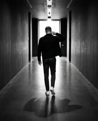High-Contrast Black and White Cinematic Portrait 7 — Nano Banana AI Prompt: The background divides into a bright field of light on one side and deep black o...