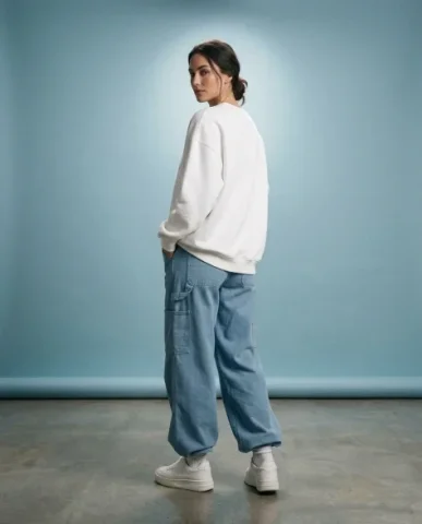 Minimalist Sky-Blue Streetwear Studio Portrait 6 — Nano Banana AI Prompt: She wears the oversized white sweatshirt with soft draping pooling around her se...