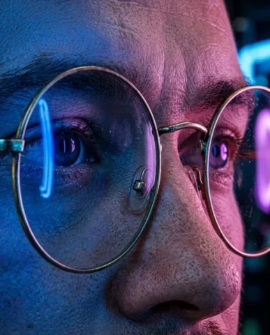Neon-Lit Cyberpunk Portrait with Round Glasses 3 — Nano Banana AI Prompt: Shallow depth of field with focal plane on the eye and glasses, ear and backgrou...