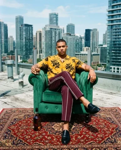 Rooftop Power Editorial with Armchair and Cityscape 1 — Nano Banana AI Prompt: Highly stylized editorial vertical photo of a confident young man with close-cro...