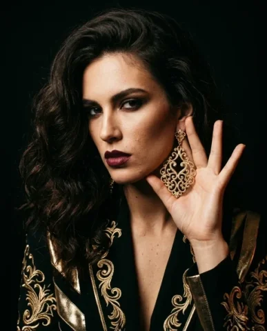 Bold Opulent Gold Statement Earring Dramatic Portrait 5 — Nano Banana AI Prompt: Dramatic studio fashion image of a female model with voluminous dark waves, bold...