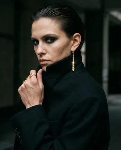 Edgy Smoky Eye Gold Earring Moody Editorial Portrait 5 — Nano Banana AI Prompt: Vertical editorial close-up of a female model in a matte black oversized blazer....
