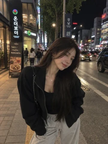 Urban Night Street Selfie Portrait — GPT Image 2.5 AI Prompt: A photorealistic nighttime street-style portrait of a young woman taking a casua...