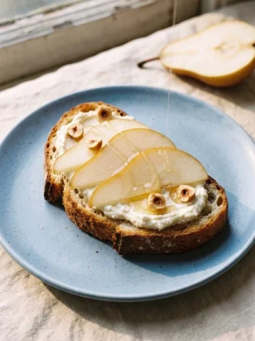Pear and Ricotta Toast — Nano Banana 2 AI Prompt: A graceful food editorial photograph of one thick slice of sourdough toast toppe...