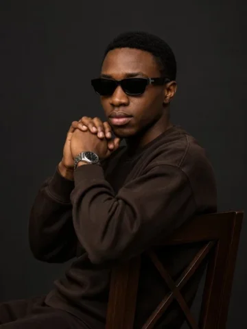 Luxury Editorial Studio Portrait — GPT Image 2.5 AI Prompt: Create a cinematic luxury editorial studio portrait of a young Black man seated...