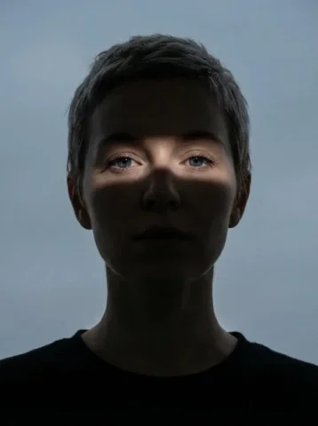 Narrow Light Band Shadow Portrait — Nano Banana 2 AI Prompt: Close-up portrait of a woman (Same face as reference image)looking directly at t...