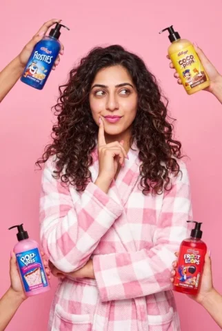 Pink Shower Gel Ad — Nano Banana 2 AI Prompt: A young woman with long, voluminous curly dark brown hair stands centered agains...