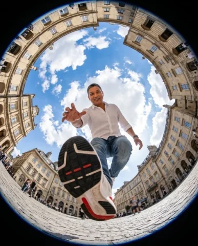 Fisheye Urban Plaza Step-Over Shot — Nano Banana 2 AI Prompt: Ultra-realistic action photography, extreme fisheye lens, 8mm, worm’s-eye view f...