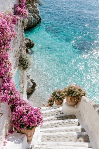 Bougainvillea Stairs to Amalfi Beach β Midjourney v6 AI Prompt: Dreamy hidden Amalfi Coast pathway descending toward a secluded beach, white sto...