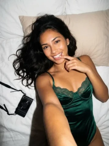 Flash Snapshot on White Sheets — Nano Banana 2 AI Prompt: { "subject": "A young woman with long, dark, wavy hair spread out behind her. Sh...