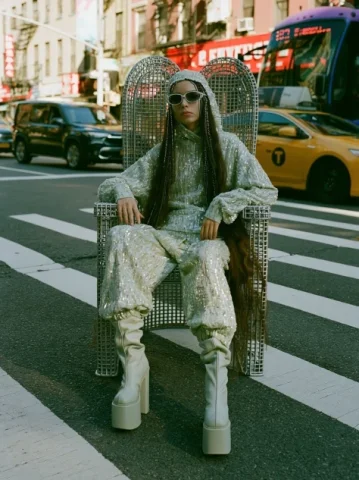 Fashionista Enthroned on a Crosswalk — Nano Banana 2 AI Prompt: A fashionista sits on a queen-like metal chair on a crosswalk. Editorial style....