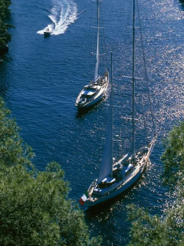 Aerial View of Classic Sailing Yachts — Nano Banana 2 AI Prompt: an aerial full shot captures two classic sailing yachts anchored in a deep blue...