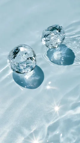 Suspended Droplets Skincare Macro — Nano Banana 2 AI Prompt: Crystal clear water droplets suspended in motion, pale blue water reflections, s...