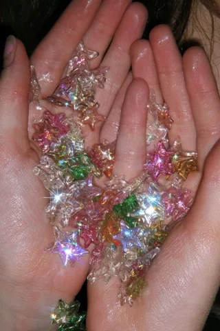 Transparent Stars and Stickers — Nano Banana 2 AI Prompt: 00s macro candid shot, a girl's palms holding many transparent, colorful plastic...