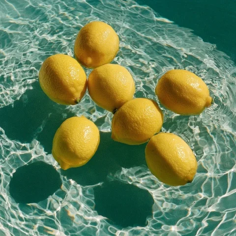 Hyperrealistic Still Life — Nano Banana 2 AI Prompt: Hyperrealistic still life, bright yellow lemons floating in a shallow turquoise...
