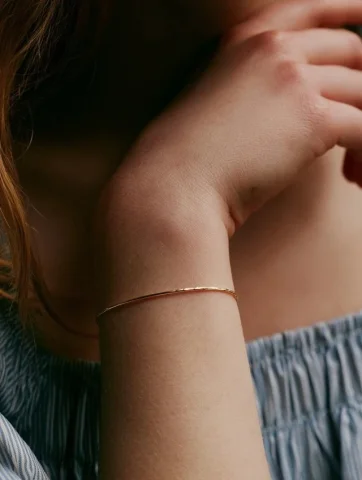 Gold Bracelet — Midjourney v6 AI Prompt: A white model, wearing a thin gold bracelet on the wrist, the camera focuses on...