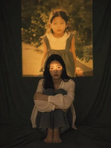 Film Projection Portrait — Nano Banana 2 AI Prompt: [인물참조 이미지1] [인물의 포즈 및 표정] 바닥에 주저앉아 무릎을 굽히고 팔로 안...