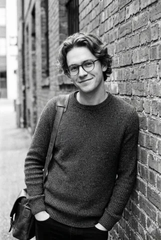 Black and White Urban Male Portrait — Nano Banana 2 AI Prompt: A vertical black and white candid portrait of a charming young man with wavy, me...