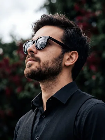 Bearded Profile Portrait — Nano Banana 2 AI Prompt: A detailed low-angle portrait of a man with a thick beard and sunglasses, set ag...