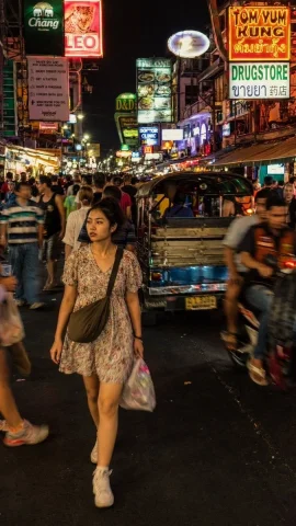 Bangkok Neon Street Photo — Nano Banana 2 AI Prompt: A street photograph capturing a young Thai woman cutting through the dense night...