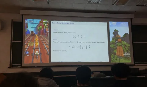 Lecture Hall Projection — Nano Banana 2 AI Prompt: A realistic photograph taken from the audience in a dimly lit university lecture...