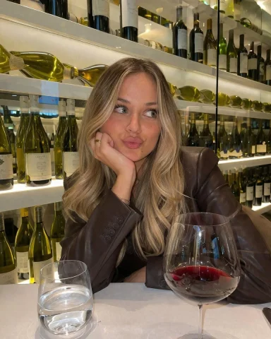 Casual Wine Bar Portrait — Nano Banana 2 AI Prompt: A photorealistic, casual smartphone photo of a young woman with long blonde bala...