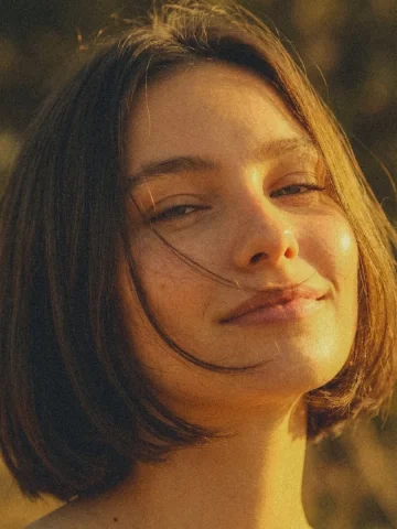 Golden Hour Short Hair Warm Close-Up Portrait — Nano Banana 2 AI Prompt: Close-up portrait of a young woman with short hair, subtle smile, face illuminat...