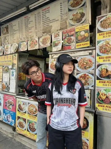 Southeast Asian Street Food Stall Esports Couple — Nano Banana 2 AI Prompt: A candid street photography shot of two young Asian adults standing in front of...