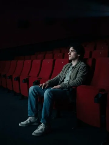 Empty Cinema Hall Solo Cinematic Portrait — Nano Banana 2 AI Prompt: Prompt: Create a realistic cinematic photo of a person using the face from the u...