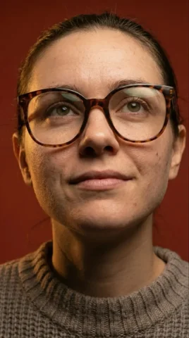 Tortoiseshell Glasses Warm Studio Close-up Portrait — Nano Banana 2 AI Prompt: A highly detailed, hyper-realistic close-up portrait of a young woman. She has n...