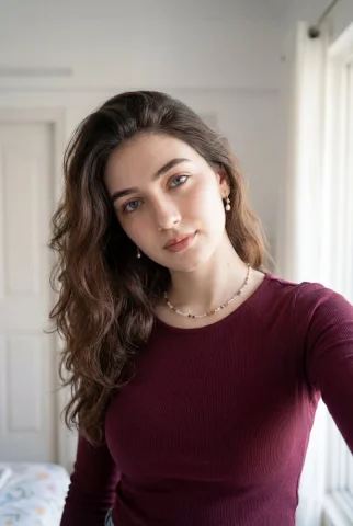 Indoor Selfie Burgundy Top Casual Portrait — Nano Banana 2 AI Prompt: Ultra-realistic portrait of a young woman taking a casual indoor selfie, soft na...