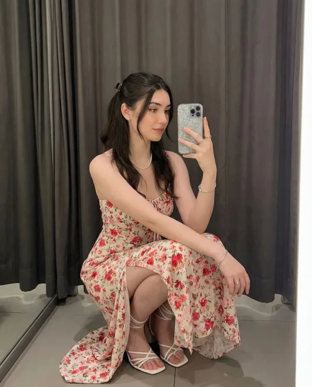Young woman elegantly squatting for a selfie indoors
